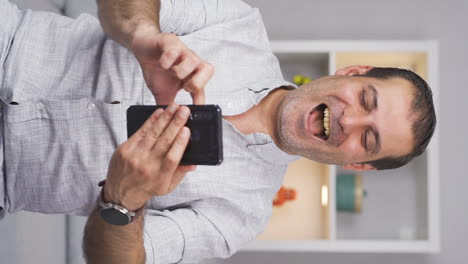 Vertical-video-of-The-man-looking-at-the-phone-is-happy.